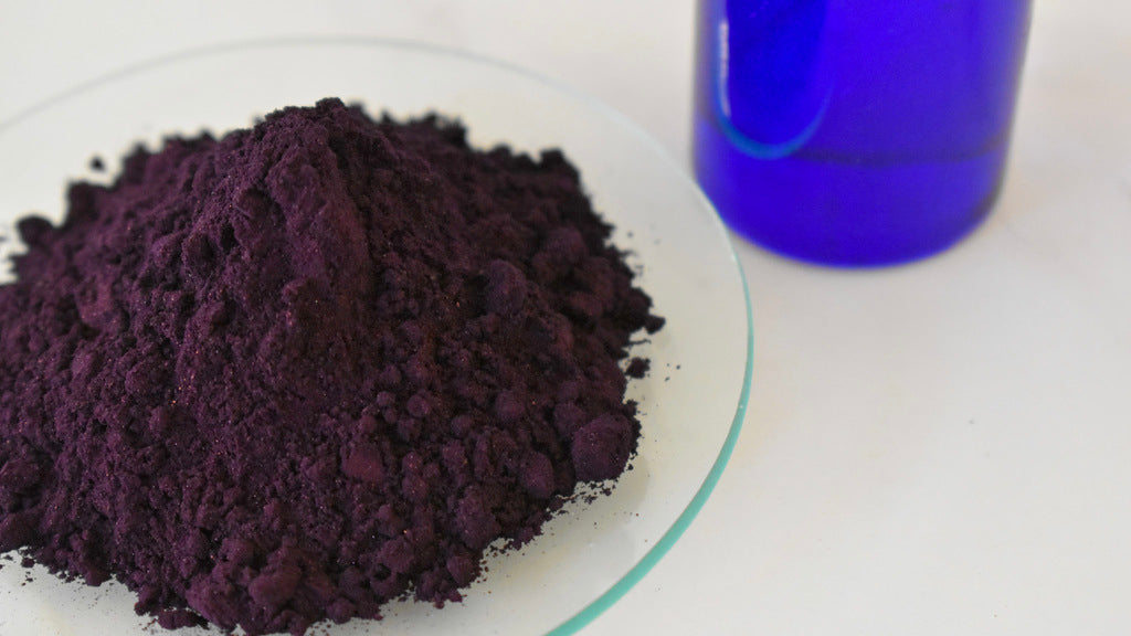 blue oil dye powder with glass beaker in background