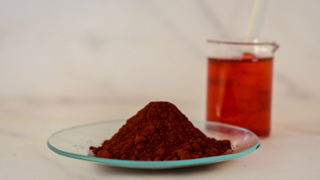 red oil dye powder on watch glass with glass beaker in background
