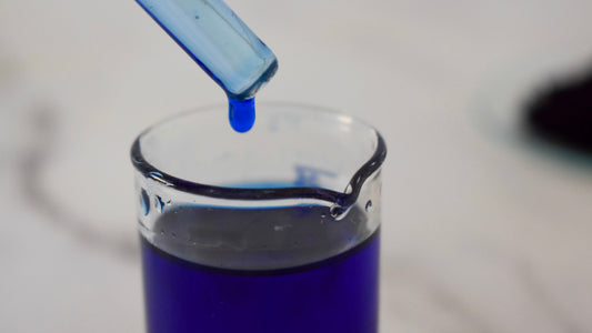 blue oil dye drop in glass beaker