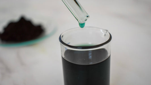 green oil dye drop in glass beaker